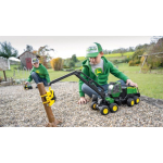 Vista frontal izquierda de un modelo de máquina forestal John Deere verde y amarilla con un brazo de grúa negro y una pinza amarilla, con la que un niño está jugando.