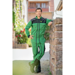 Pełnowymiarowy widok mężczyzny w zielono-czarnym kombinezonie roboczym John Deere i czarnych butach roboczych, stojącego i pochylającego się.