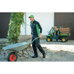 Un hombre con una gorra verde de John Deere, un forro polar verde y negro con cremallera hasta el pecho y pantalones de trabajo negros, empujando una carretilla.