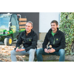 Twee mannen met zwarte John Deere softshell-jacks met groene logo's en ritssluitingsdetails zitten buiten.