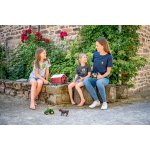 A woman in a dark blue John Deere t-shirt and two girls in gray John Deere t-shirts sit outdoors with John Deere toys and a mug.