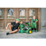 Mężczyzna w czapce John Deere i dwóch chłopców w odzieży roboczej John Deere pozują z zielonym zabawkowym ciagnikiem John Deere.