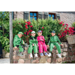Quatro crianças vestidas com roupa de trabalho e bonés John Deere verdes e cor-de-rosa estão sentadas lado a lado num muro de pedra.